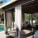 A cabana with a sofa, snacks on a coffee table, a cucumber infused water station and padded chairs next to a pool